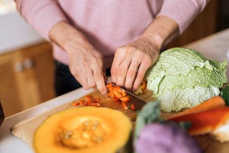 Unrecognized handsome man cutting vegetables in the kitchen at home.