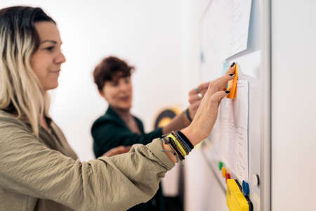 Young business women writing on whiteboard during brainstorming process.の写真素材