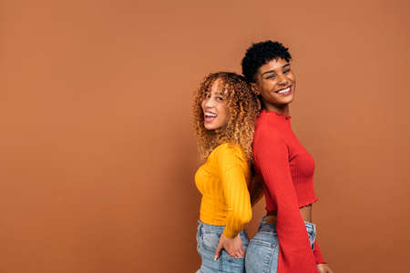 Stock photo of cheerful afro women posing in studio shot against brown background.の写真素材