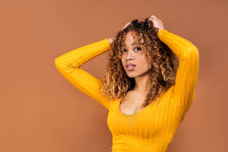 Stock photo of expressive young woman posing in studio shot against brown background.の写真素材
