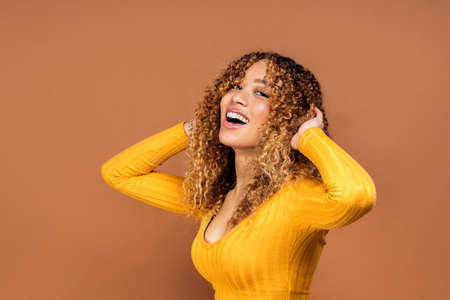 Stock photo of attractive young woman posing in studio shot against brown background.の写真素材