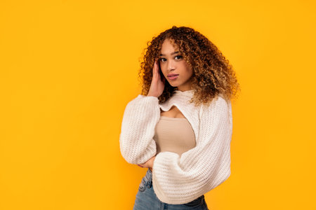 Stock photo of attractive young woman posing in studio shot against yellow background.