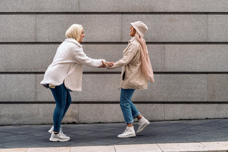 Affective young women wearing hijab laughing and walking in the street.