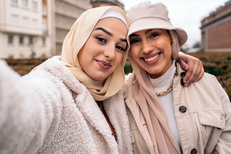 Cheerful girls wearing hijab having fun and taking selfie in the street.の写真素材
