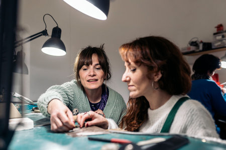 Concentrated adult women working in jewelry workshop.の写真素材