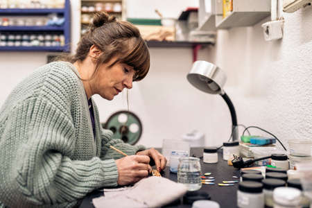 Stock photo of adult woman using paint in jewelry workshop.の写真素材