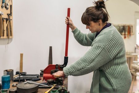Stock photo of adult woman using tools in jewelry workshop.
