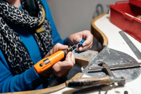 Unrecognized craftswoman working jewelry workshop using tools.の写真素材