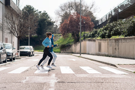 Cheerful active girls wearing sports clothes running and crossing the street.の写真素材