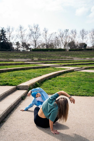 Muslim girl with hijab stretching with her friend in the park after workout.の写真素材
