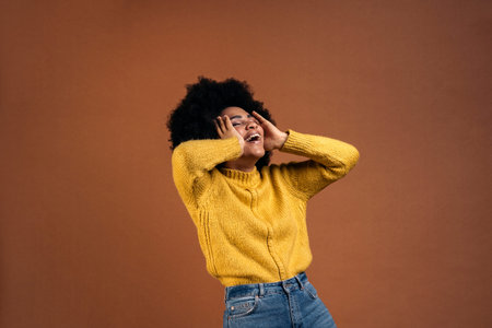 Smiley afro girl having fun in studio shot against brown background.