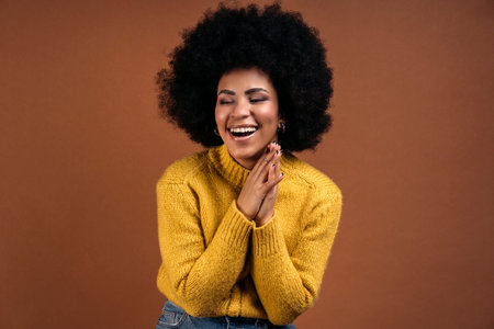 Smiley afro girl having fun in studio shot against brown background.の写真素材
