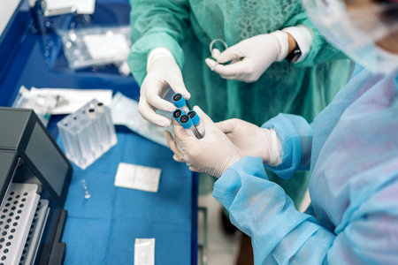 Professionals medic workers wearing latex gloves looking at sample tubes in the lab.