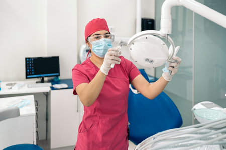 Female dentist working in modern dental clinic and wearing face mask. She is also wearing dental safety glasses.の写真素材