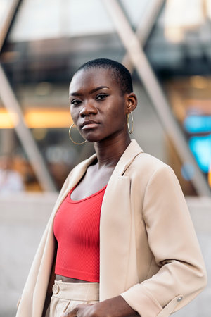 Vertical image of an elegant african american young adult woman with short hair standing and looking...