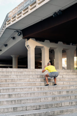 Rear view of an unrecognizable African American man doing squats exercises on stairs outdoor