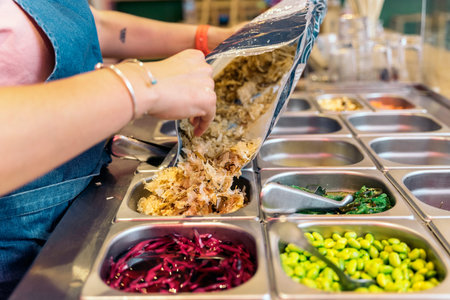 Unrecognized restaurant worker preparing ingredients for poke bowl.