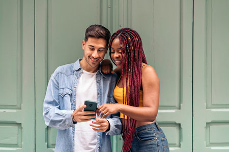 Multicultural young friends using their phone in the city and having fun.の写真素材