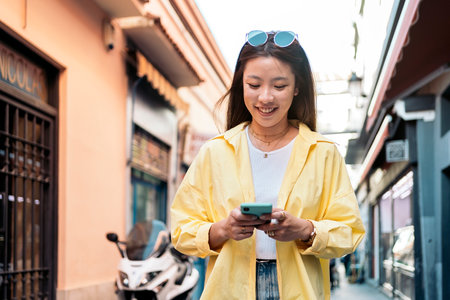 Cool asian woman with trendy clothes walking in the city and using her smart-phone. cの写真素材