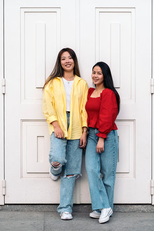 Happy young asian female friends smiling and looking at camera against white background.