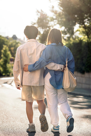 Unrecognized young couple walking in the city of Madrid and hugging each other.の写真素材