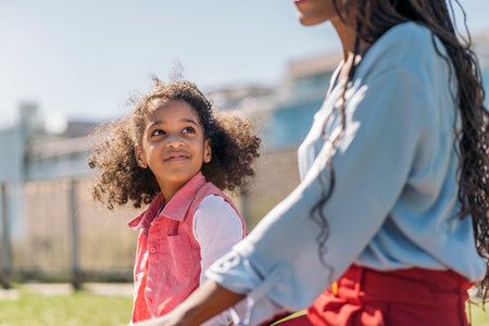 Adorable young black girl with afro hair playing in the park with her mother and having fun.の写真素材