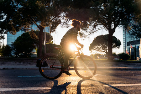 Cool hipster man with big beard riding his bike in the street during the evening and looking at front.の写真素材