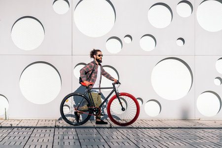 Confident man with long beard walking in the street with his cool bike.の写真素材