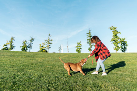 Unrecognized woman playing in the park with her purebred dog and having fun.の写真素材