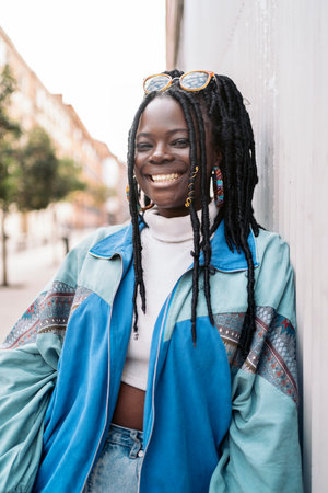 Happy and young african woman with cool braids smiling and looking at camera. She is in the street.の写真素材