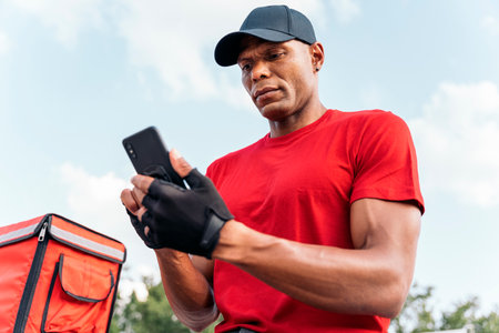 African messenger man using his phone in the street on his way to deliver a package.の写真素材