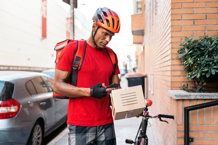 African messenger man preparing package for delivery in the destination and using his phone.の写真素材