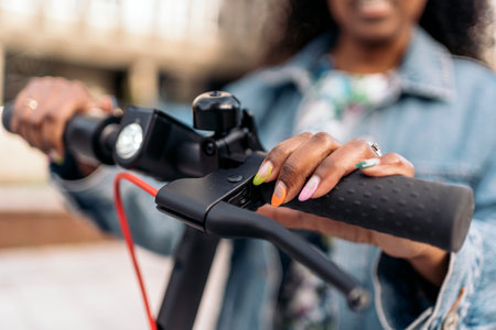 Unrecognized black woman turning on her electric scooter in the street.の写真素材