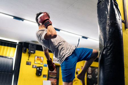 Kickboxing fighter performing Kicks with Knee on punching bag at the gym. Concept of kickboxing.の写真素材