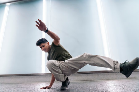 Talented boy practicing break dance against white wall with lights and having fun.の写真素材