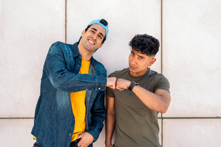 Happy and cool male friends smiling and looking at camera against white wall.の写真素材