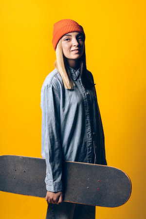 Stock photo of young expressive girl looking at camera in studio. She is holding a skateboard.の写真素材