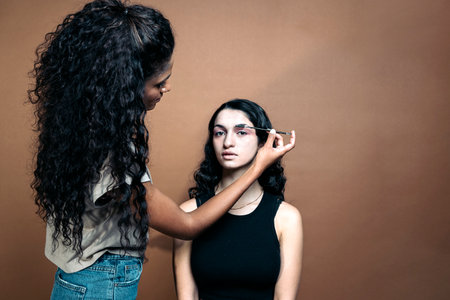 Stock photo of beautiful young woman doing makeup to her client in studio.の写真素材