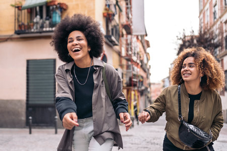 Stock photo of casual happy afro girls laughing and walking in the city.の写真素材