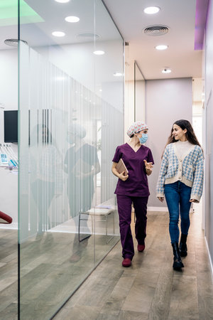 Stock photo of female dentist wearing face mask talking with her young patient in the dental clinic.の写真素材