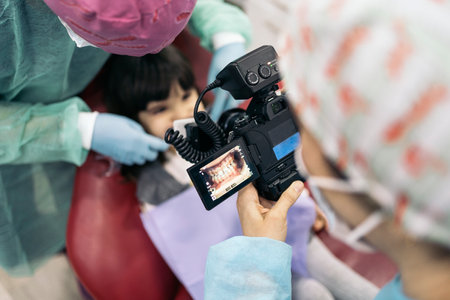 Stock photo of female dentist wearing face mask taking picture of a young patient.の写真素材