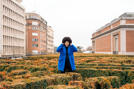 Stock photo of young afro girl with blue coat having fun in beautiful garden.の写真素材