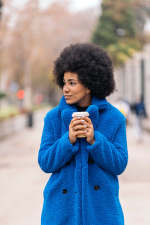 Stock photo of cool afro girl looking to the side and having a cup of coffee.の写真素材