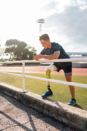 Disabled man athlete using his phone while doing a break.の写真素材
