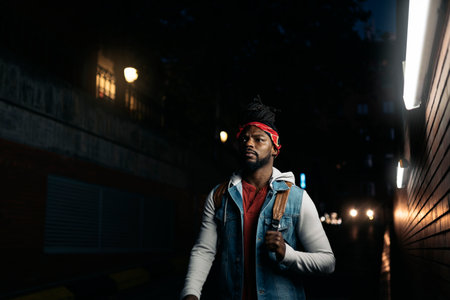Stock photo of serious african american boy with dreadlocks walking in the street at night.の写真素材