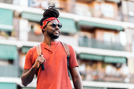 Stock photo of happy african american boy with dreadlocks and a bandana walking in the street.の写真素材