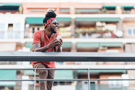 Stock photo of attractive african american boy with dreadlocks and a bandana using his phone. He is laughing.の写真素材
