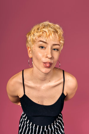Stock photo of funny girl with her tongue out looking at camera over pink background.の写真素材
