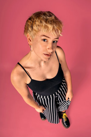 Stock photo of expressive girl wearing black tank top standing and looking at camera over pink background.の写真素材