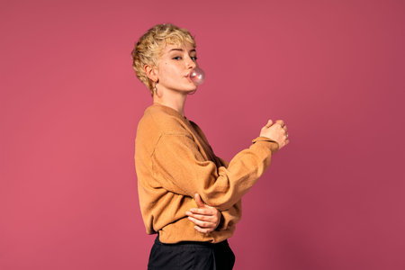Stock photo of young girl blowing bubble with chewing gum during studio shot.